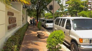 A pathway lined with parked cars and small trees, leading to a building with a sign that reads "RUTZ CHRG." - Luxurious Ocean View Studio Next to Major Hotels (Carolina)