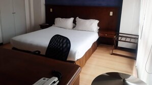 Una camera d'albergo con un letto grande, una scrivania con il telefono e un comodino.