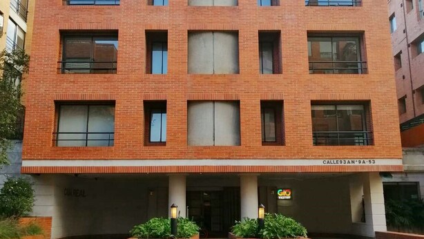 Edificio a più piani con facciata in mattoni, ampie finestre e un ingresso centrale con gradini.