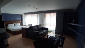 Una moderna camera d'albergo con un letto, un divano, un tavolino e una televisione.