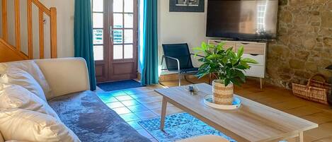 A living room with a sofa, a coffee table, a TV, and a stone wall.