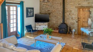 A living room with a sofa, a TV, a fireplace, and a stone wall. - Gorgeous home in St. Pierre Langers (St. Pierre Langers)