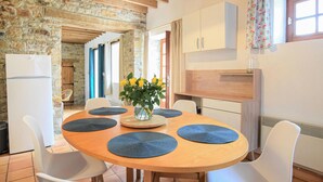 A dining area with a round wooden table, white chairs, and blue placemats. A vase with yellow flowers is on the table. - Gorgeous home in St. Pierre Langers (St. Pierre Langers)