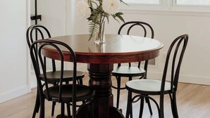 A dining area with a round wooden table, black chairs, and a woven orange pendant light. - CITY COTTAGE, CITY COTTAGE GETWAY, FENCE BACKYARD (Saint Paul)