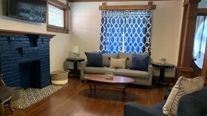 Un salon avec une cheminée, un canapé, une table basse et un tapis à motifs.