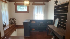 Une salle d’étude équipée d’un bureau en bois, d’étagères et d’une grande fenêtre avec des stores.