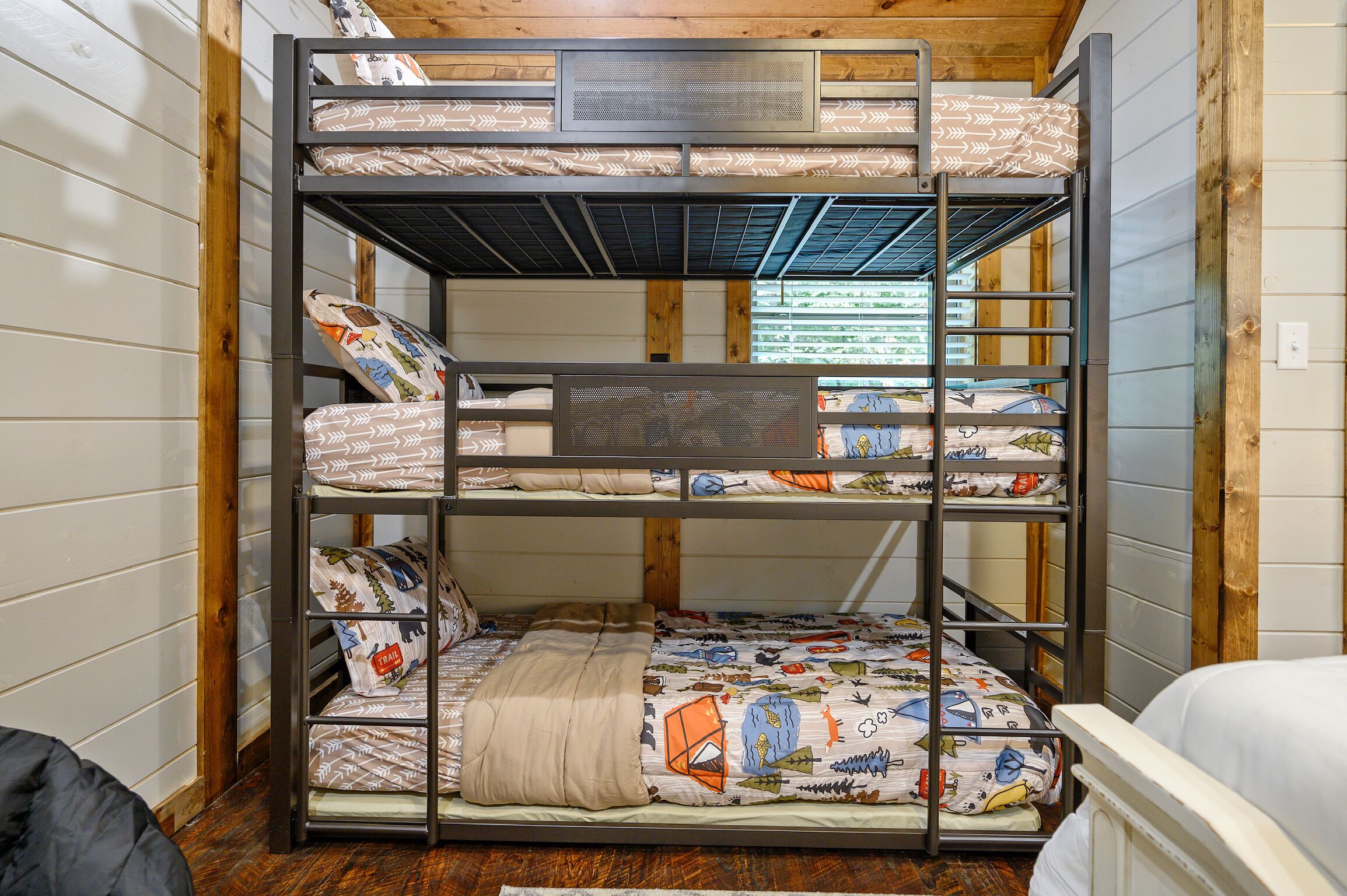 Un lit superposé à trois niveaux, chaque niveau étant doté de draps et d’oreillers à motifs.