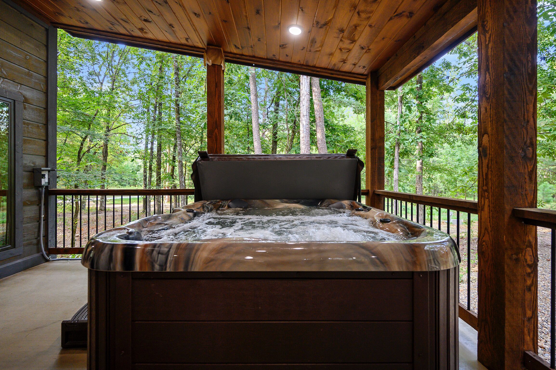 Un jacuzzi en una cabaña de madera con vistas a un bosque.