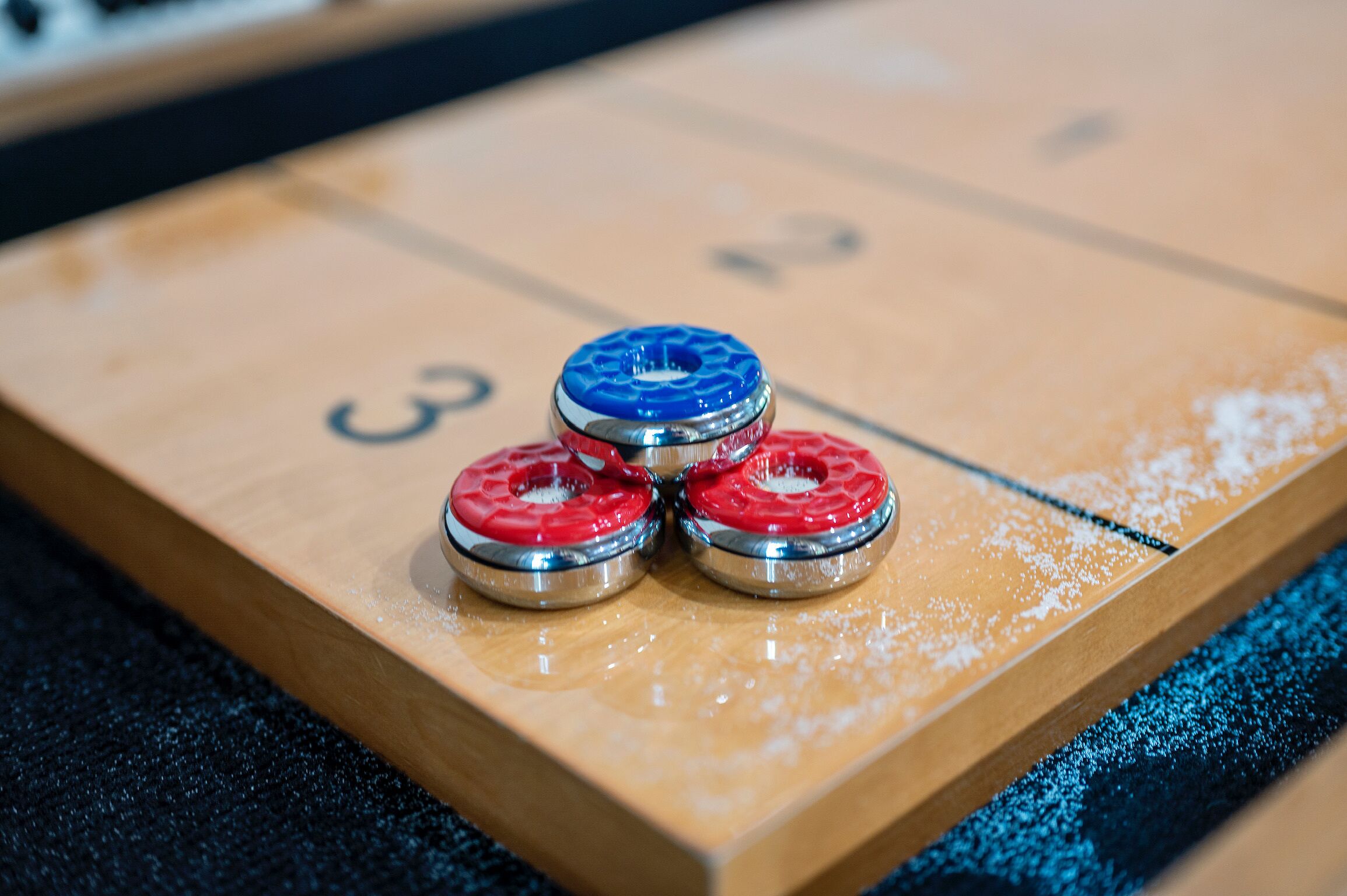 Three shuffleboard pucks on a numbered board.