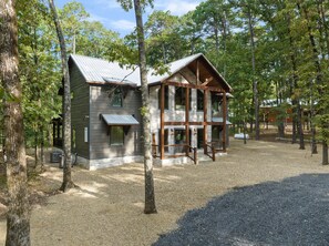 A two-story log cabin with a metal roof, surrounded by trees. - NEW!! Escape to Modern Luxury in Broken Bow, Oklahoma! Blissful Pines Sleeps 14! (broken bow)