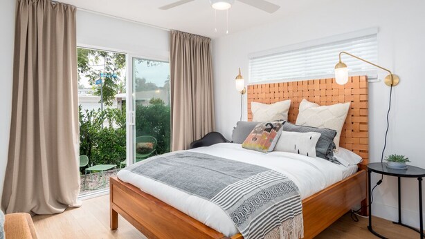 Un dormitorio moderno con una cama de madera, un ventilador de techo y vistas al exterior.