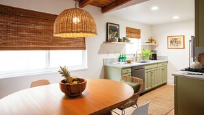 Una cocina moderna con vigas de madera, una mesa de comedor con frutero y armarios verdes.