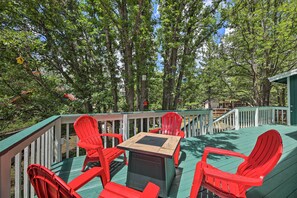 A deck with red chairs and a table, surrounded by trees. - Deck + Yard: Family-Friendly Pinetop Retreat (Pinetop)