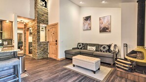 Un salon moderne avec une cheminée en pierre, un canapé d’angle gris et un coin bar.