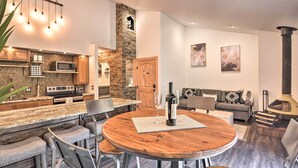 Une cuisine moderne avec un mur d’accent en pierre, un coin repas doté d’une table ronde en bois et un espace de vie chaleureux agrémenté d’une cheminée.
