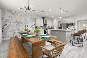 Una cocina moderna con una mesa de comedor de madera, taburetes de bar y un salpicadero con diseño floral.