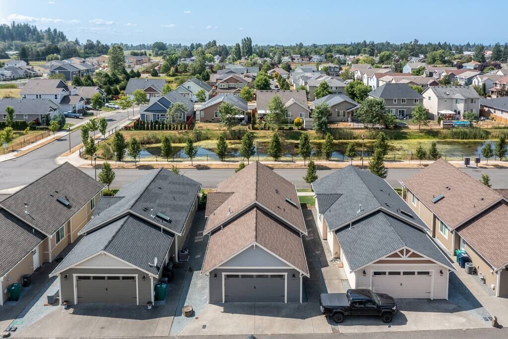 A suburban neighborhood with detached houses, a central road, and a small body of water.