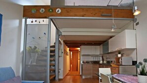 Une cuisine moderne avec des meubles blancs, une table à manger et un escalier menant à l’étage supérieur.