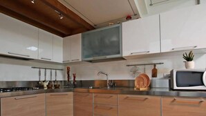 Une cuisine moderne dotée d’appareils électroménagers en acier inoxydable, de meubles en bois et d’un four à micro-ondes encastré.