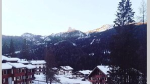 Un quartier résidentiel enneigé, avec des immeubles à plusieurs étages, un ciel dégagé et une montagne en arrière-plan.