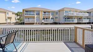 A waterfront hotel with balconies, a deck, and a pool.