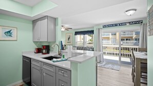 A kitchen with a sink, cabinets, and a coffee maker. There is a sign that reads "Salt Therapy" and a view of a balcony with a railing.