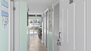 A hallway with a wooden floor, white doors, and a sign indicating 'No Smoking'.