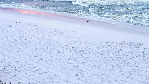 A beach with waves and a sunset.