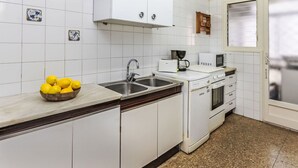 A kitchen with white cabinets, a sink, a stove, and a microwave. There is a bowl of lemons on the counter.