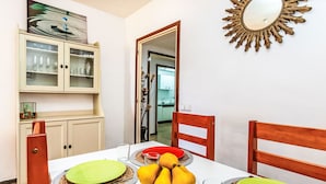 A dining area with a table set for four, including plates, cutlery, and a bowl of fruit.