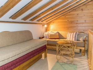 Ein gemütliches Schlafzimmer im Dachgeschoss mit einer Schlafcouch, einem Bett und einem kleinen Tisch.