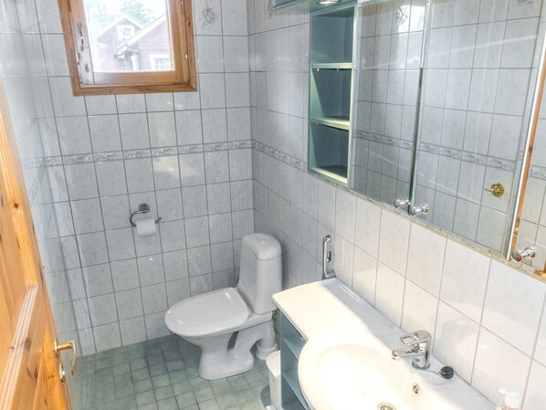 A small bathroom with a toilet, sink, and mirror.