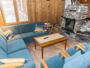 A cozy living room with a blue sofa, a wooden coffee table, and a stone fireplace. - Lauri 4 iso by Interhome (Kittilä)