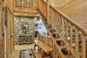 A wooden interior with a stone wall, wooden bench, and a staircase.