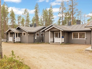 A row of cabins with a gravel driveway, surrounded by tall pine trees. - Lauri 5 by Interhome (Kittilä)
