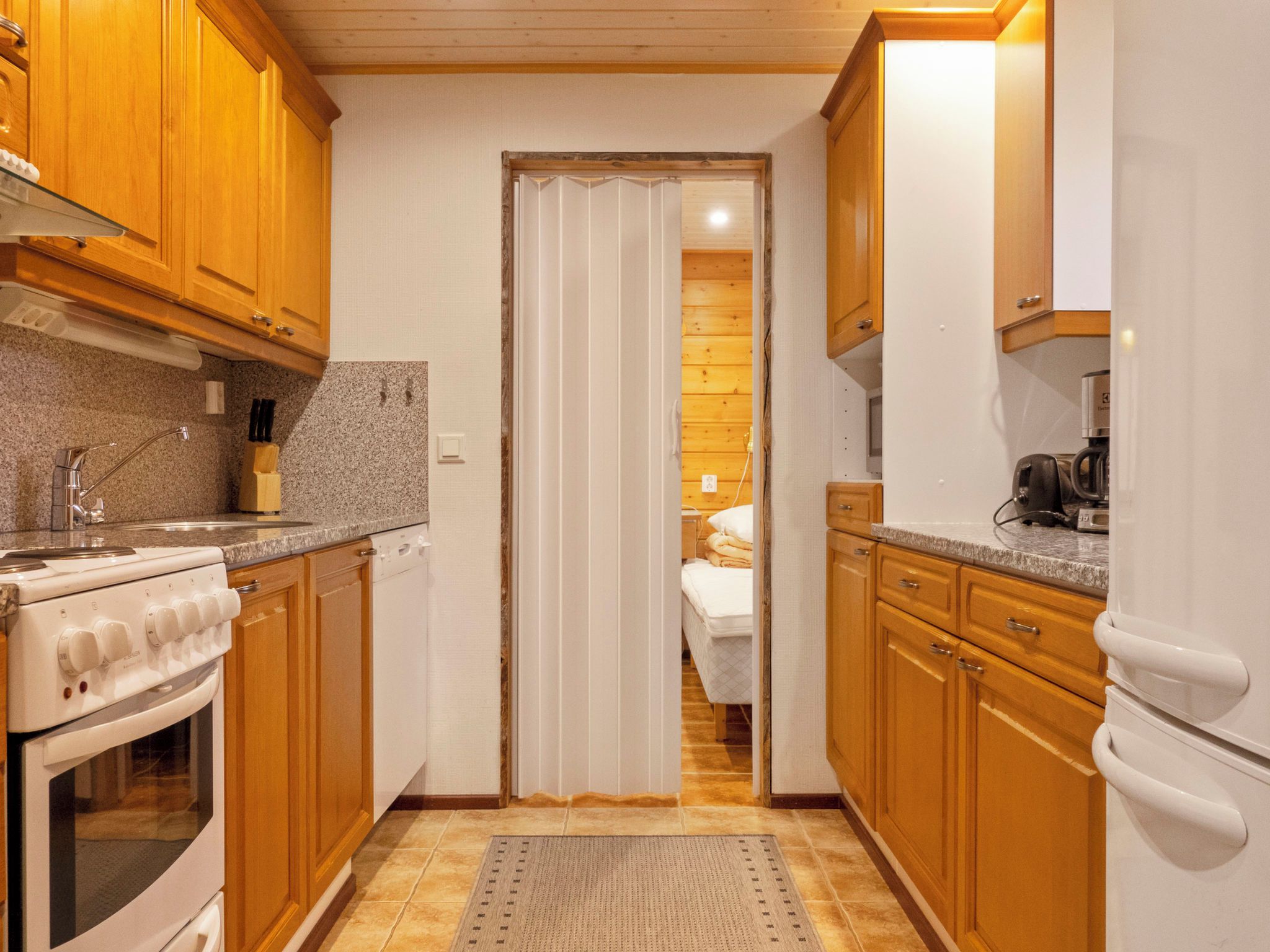 A compact kitchen with wooden cabinets, a stove, and a refrigerator.