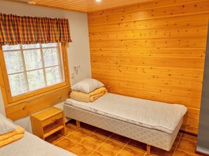 A small, cozy room with a single bed, a nightstand, and a window with blinds. - Lauri 5 by Interhome (Kittilä)
