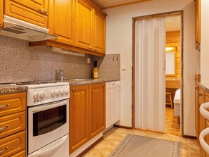 A kitchen with wooden cabinets, a built-in oven, a stove, and a dishwasher. - Lauri 5 by Interhome (Kittilä)