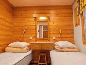 A wooden cabin room with two beds, a small stool, a mirror, and a wooden dresser. - Lauri 5 by Interhome (Kittilä)