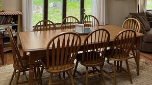 A dining area with a large wooden table and chairs, a chandelier, and a view of the outdoors. - Fire Pit, Babbling Brook, Poker & Foosball at this 3br+ home (Lakeville)