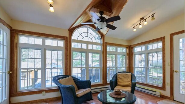 A spacious room with large windows, two wicker chairs, a small table, and a ceiling fan. - Fire Pit, Babbling Brook, Poker & Foosball at this 3br+ home (Lakeville)