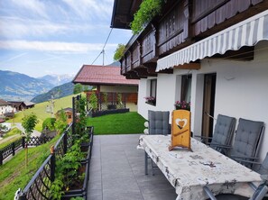 Ein traditionelles Chalet mit Balkon, einem Tisch mit einem herzförmigen Schild und Blick auf die Berge.