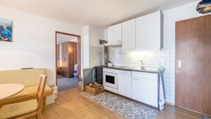 Une cuisine compacte avec des meubles blancs, un four encastré et un petit plan de travail.