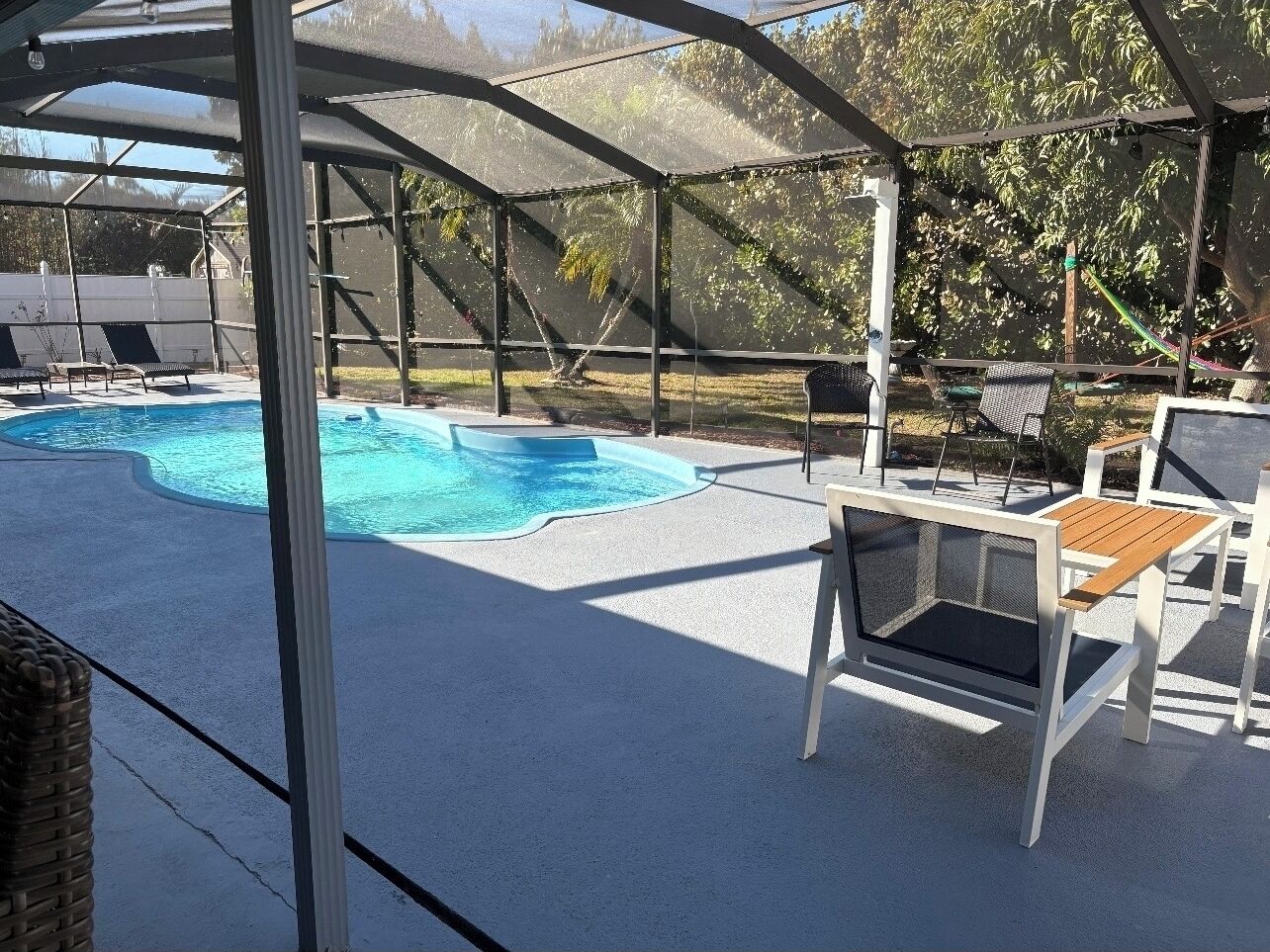 A covered outdoor swimming pool with lounge chairs and a table.