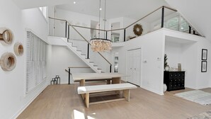 Un área de estar amplia con un banco de madera, una escalera y un candelabro.