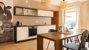 A modern kitchen with a wooden dining table, black chairs, and a large black and white cow painting on the wall. - Apartment "Anneliese" with Terrace, Garden & Wi-Fi (Neukirch)