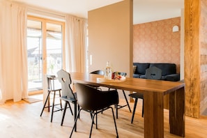 A modern living room with a wooden dining table, black chairs, a sofa, and a large window with curtains. - Apartment "Anneliese" with Terrace, Garden & Wi-Fi (Neukirch)