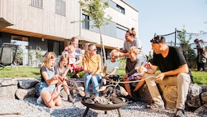 A group of people gathered around a fire pit in an outdoor setting with a modern building in the background. - Holiday Apartment "Liselotte" with Terrace, Garden & Wi-Fi (Neukirch)