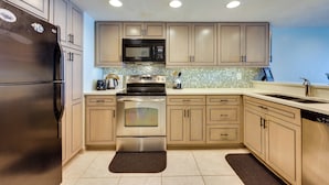 Una cucina moderna con elettrodomestici in acciaio inossidabile, mobili color beige e piastrelle a parete.
