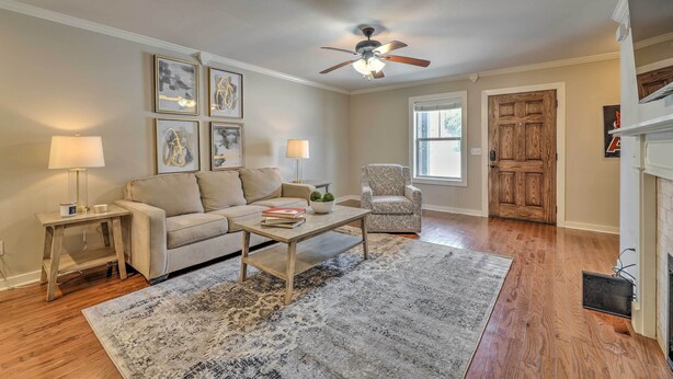 A living room with a beige sofa, a coffee table, a patterned rug, a ceiling fan, and a wooden door. - Charming Springdale Townhome ~ 5 Mi to Dtwn! (Springdale)